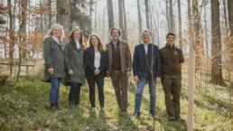 eine gruppe menschen steht im wald hinter dem neu gepflanzten baum