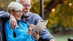 eine ältere frau und ein älterer mann halten ein tablet in der hand