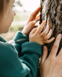 kleinkind mit mutter berührt einen baumstamm